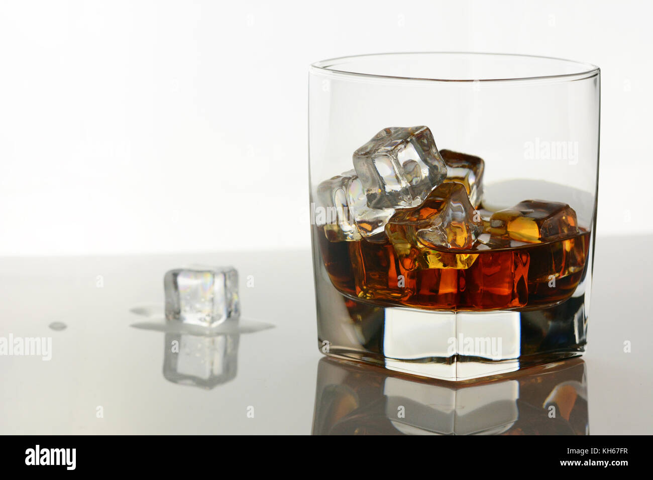 Une boisson alcoolisée sur une table en verre avec un cube de glace fondante Banque D'Images