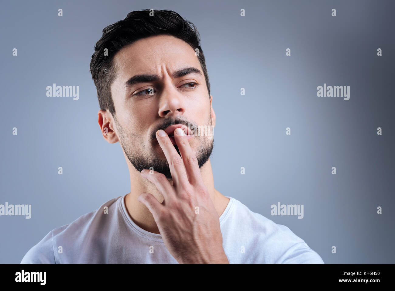 Jeune homme intelligent en appuyant sur ses deux doigts sur les lèvres en pensant Banque D'Images