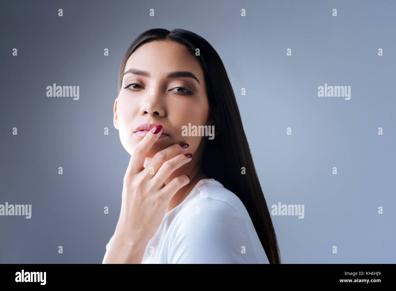 Jeune femme passionnée de toucher ses lèvres roses et légèrement smiling Banque D'Images
