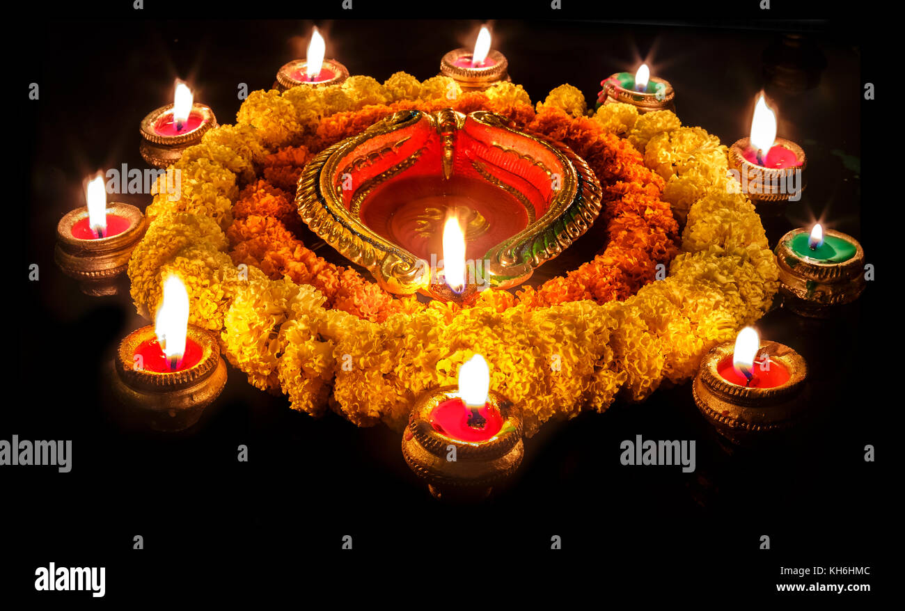 L'argile du Diwali diya lampes avec des décorations florales en fond sombre Banque D'Images