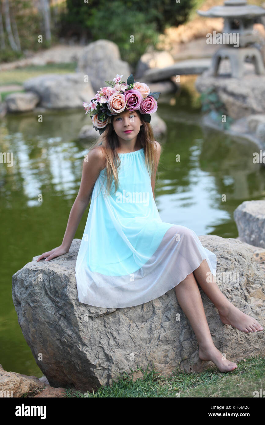 Une belle jeune fille de 12 ans habillé dans une robe bleu clair, portant une couronne de fleurs portefeuille bat mitzvah. Banque D'Images