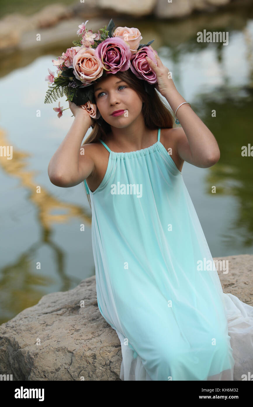 Une belle jeune fille de 12 ans habillé dans une robe bleu clair, portant une couronne de fleurs portefeuille bat mitzvah. Banque D'Images