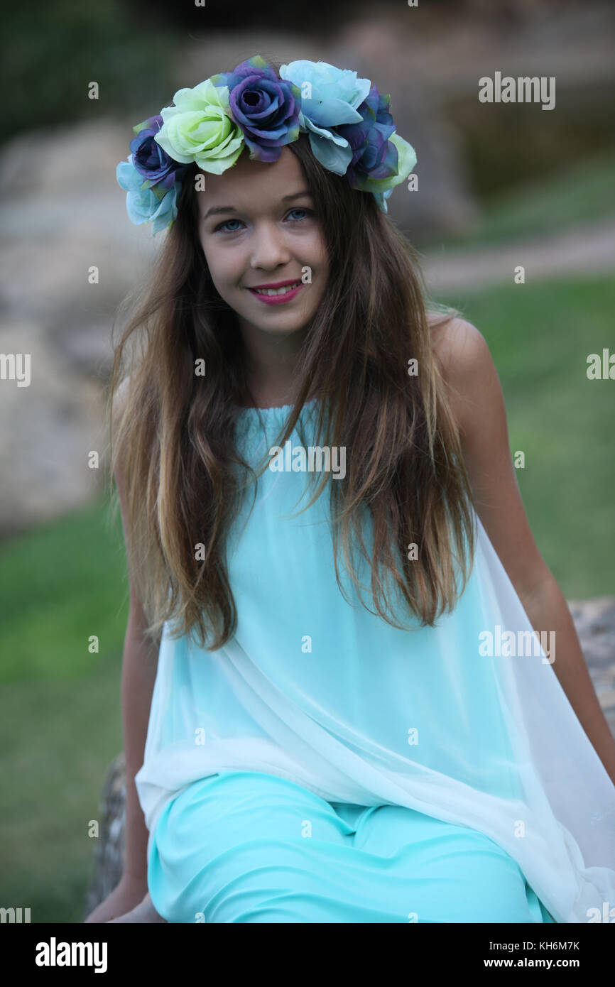 Une belle jeune fille de 12 ans habillé dans une robe bleu clair, portant une couronne de fleurs portefeuille bat mitzvah. Banque D'Images