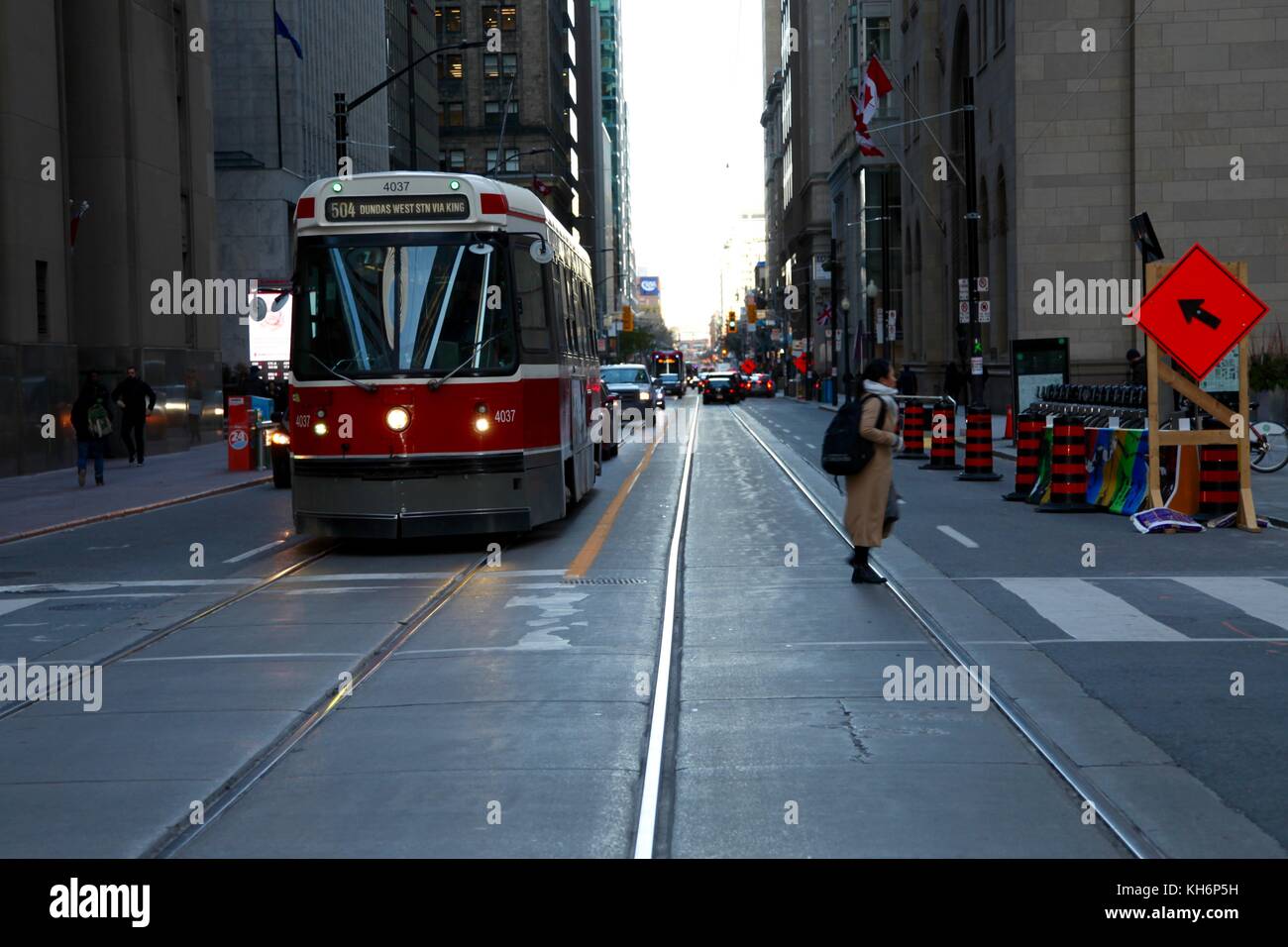 Femme de traverser la rue dans le centre-ville de Toronto en face d'une TTC streetcar Banque D'Images