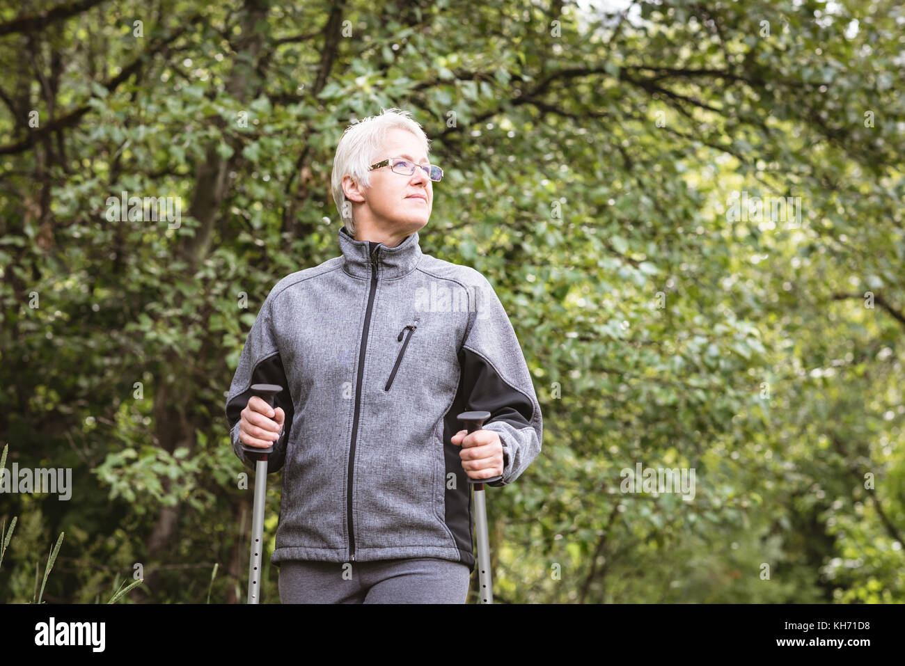 Senior woman hiker marcher avec des bâtons de marche dans la forêt Banque D'Images