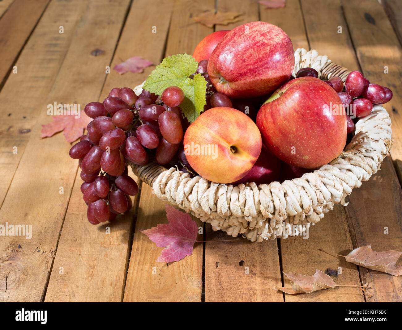 Panier de raisins, de pommes et de pêche sur une surface en bois Banque D'Images