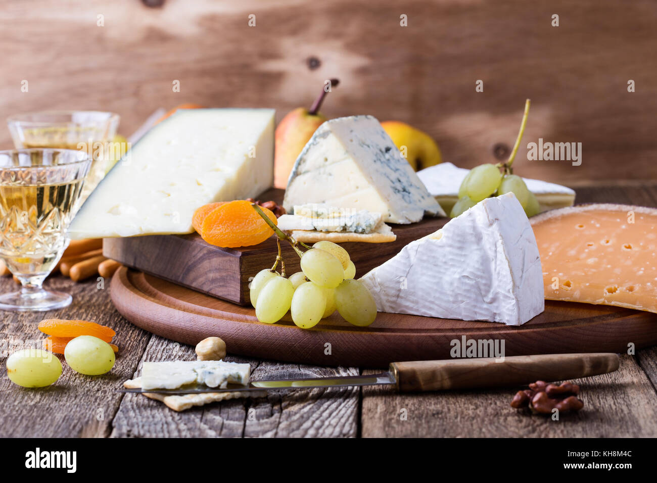Fromage, fruits et vin planche à découper en bois, de délicieux amuse-bouche sur fond de table rustique Banque D'Images