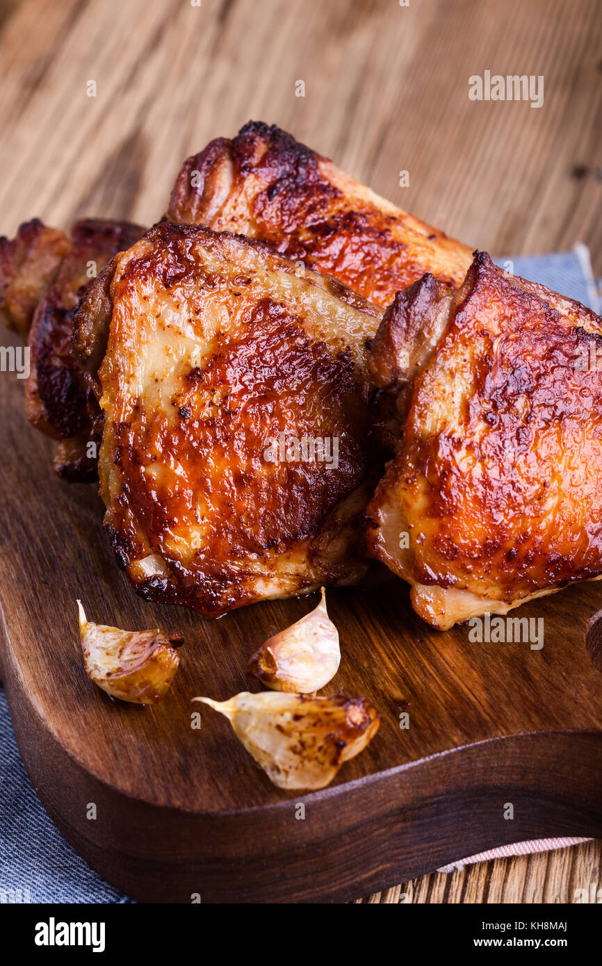 Cuisses de poulet rôti à l'ail sur la planche à découper en bois rustique Banque D'Images
