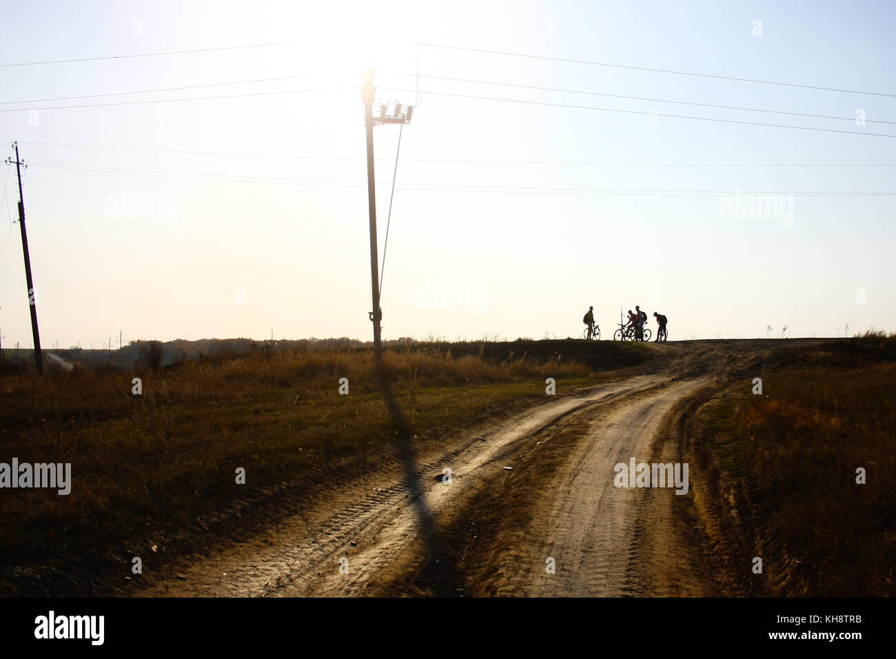 Silhouette de quatre cyclistes sur une route de gravier ouvert Banque D'Images
