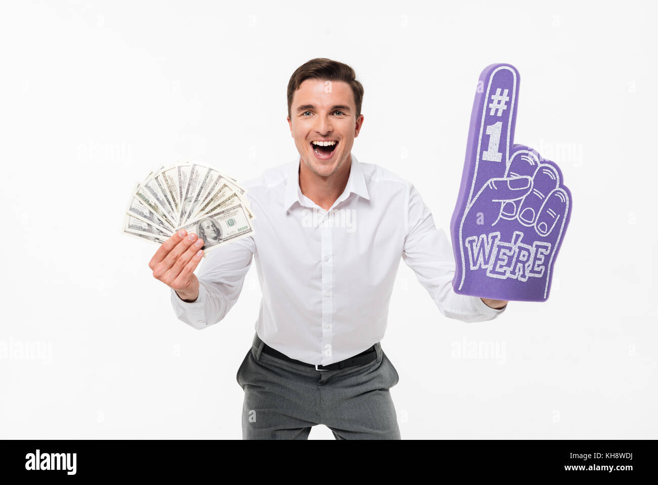 Portrait d'un homme excité amusé en chemise blanche holding tas de billets et de l'argent portant des doigt de mousse isolé sur fond blanc Banque D'Images