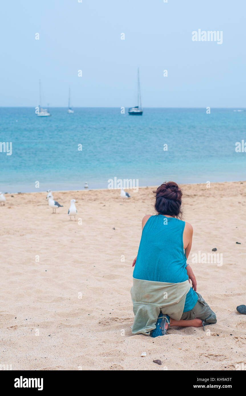 Femme mature à pattes jaunes regardant goélands argentés (Larus michahellis) sur la plage, à la Graciosa, îles de Canaries, Espagne Banque D'Images