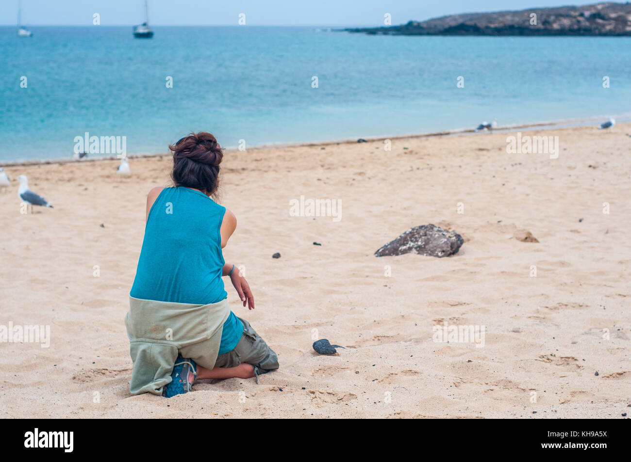 Femme mature à pattes jaunes regardant goélands argentés (Larus michahellis) sur la plage, à la Graciosa, îles de Canaries, Espagne Banque D'Images