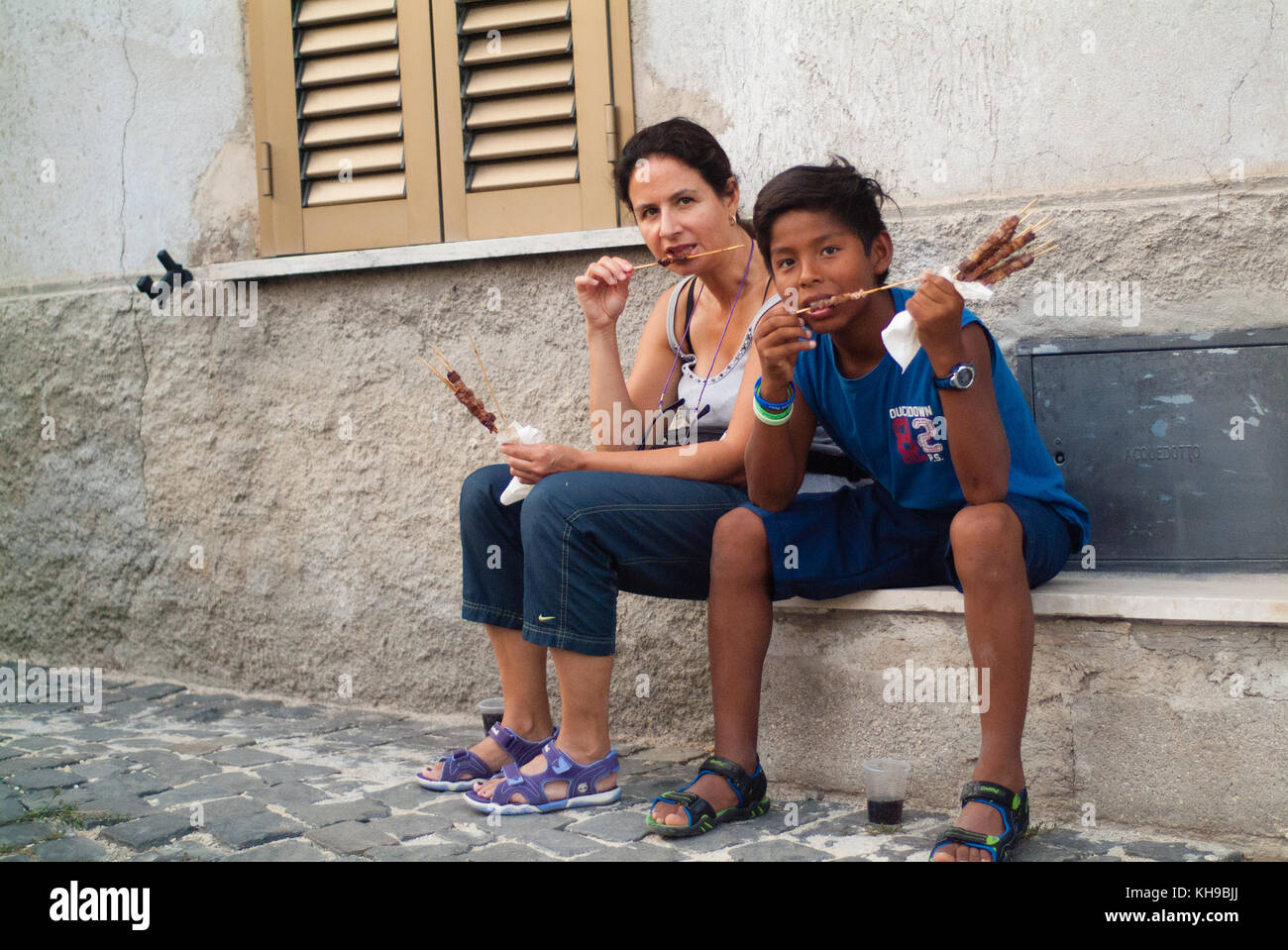 L'enfant et sa maman manger une nourriture traditionnelle du sud de l'Italie appelé arrosticini. Santo Stefano, Cammino dei Briganti. Les promenades de brigands Banque D'Images