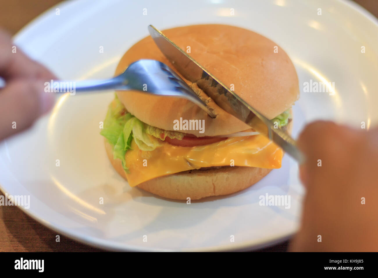 Préparer la coupe burger en moitiés deux sélectionner focus, holding burger burger de coupe, coupe en deux moitiés sur table Banque D'Images