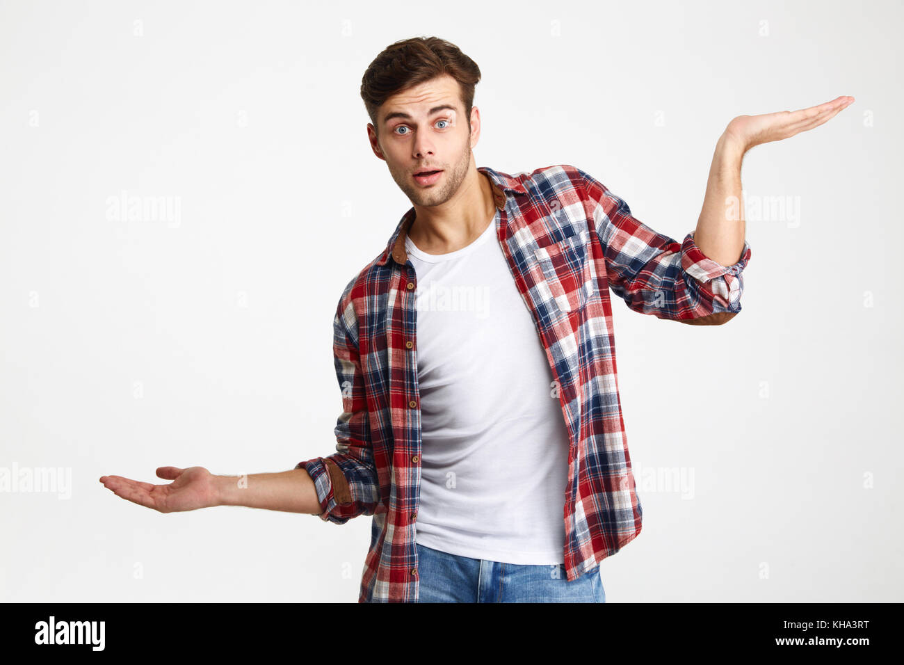 Portrait d'un surpris casual man holding copyspace sur deux palmiers isolated over white background Banque D'Images