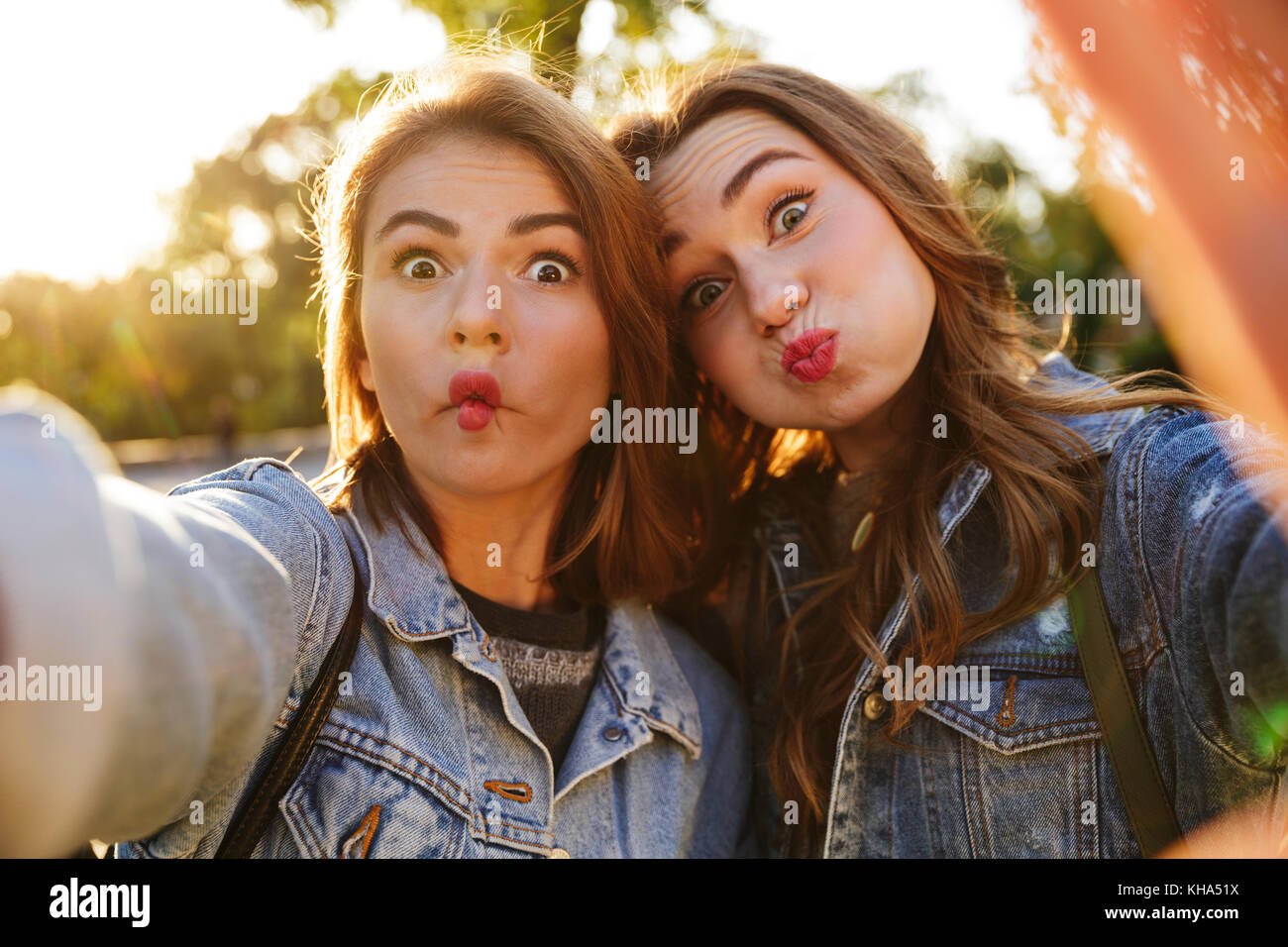 Portrait de deux jeunes filles faire des grimaces tout en prenant un extérieur selfies Banque D'Images