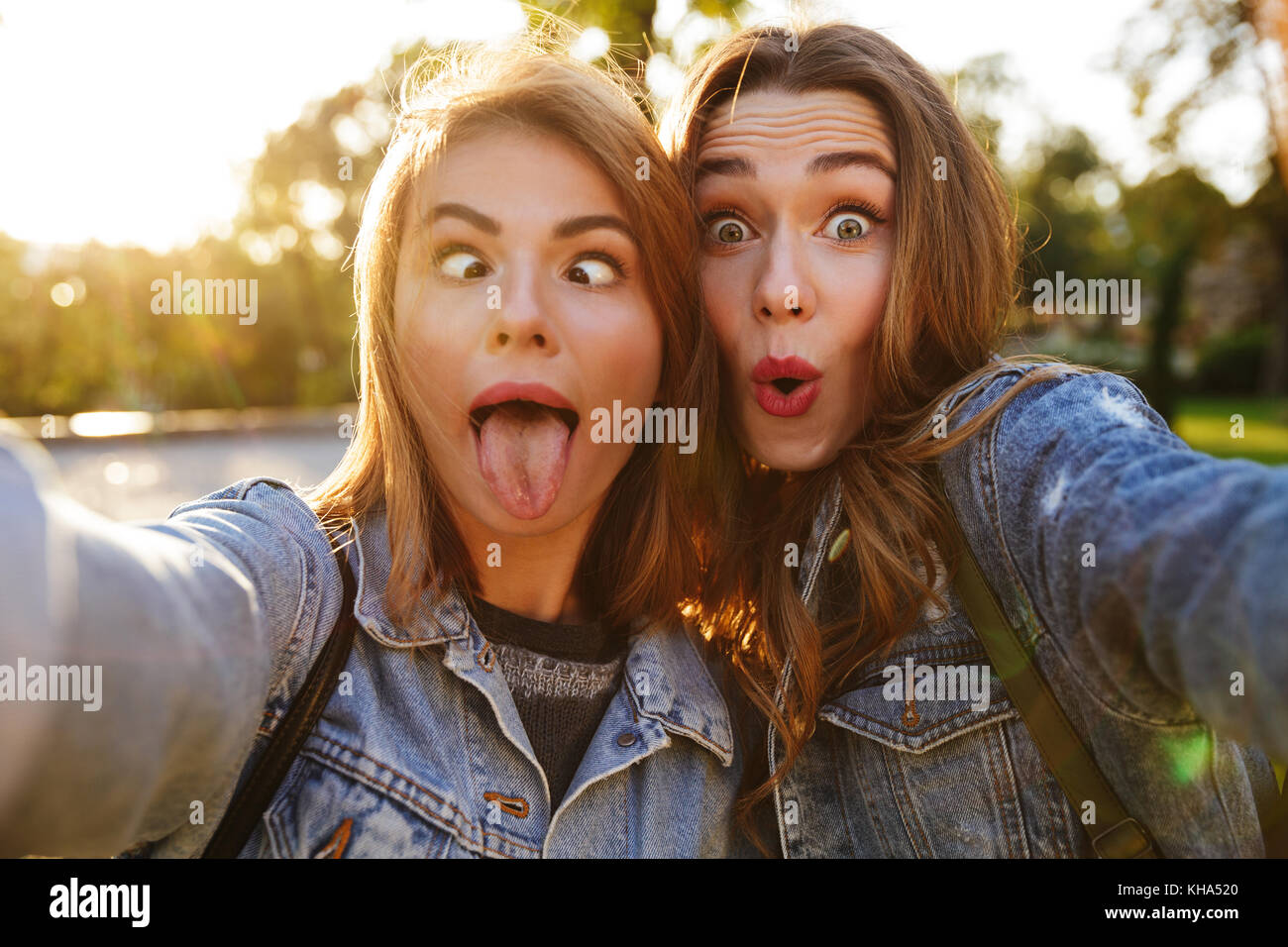 Portrait de deux jeunes filles gaies faire des grimaces tout en prenant un extérieur selfies Banque D'Images