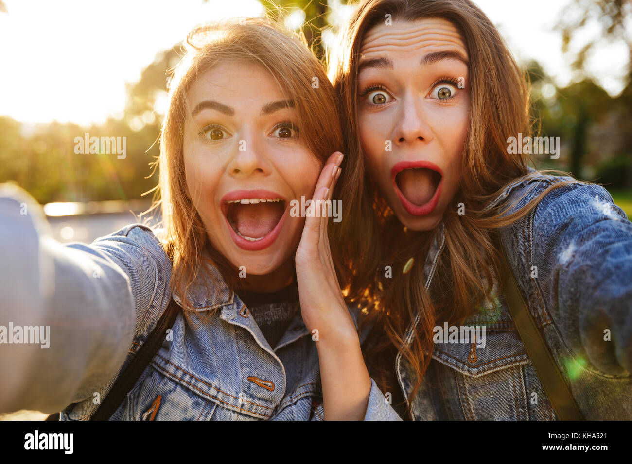 Portrait de deux cris choqué les filles faire des grimaces tout en prenant un extérieur selfies Banque D'Images