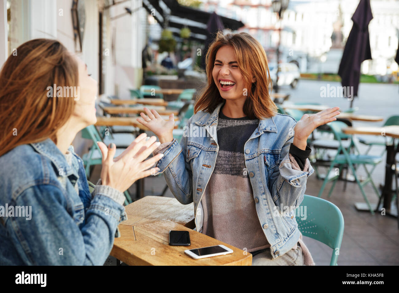 Deux jeunes filles émotionnelle la conversation tout en siégeant dans city cafe Banque D'Images