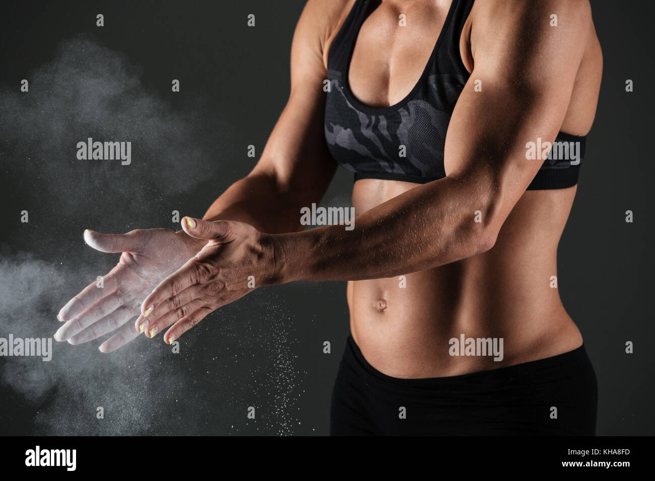 Portrait d'une grande sportive musculaire frappant des mains avec de la poudre de talc avant de faire de l'arrière-plan gris plus isolés Banque D'Images