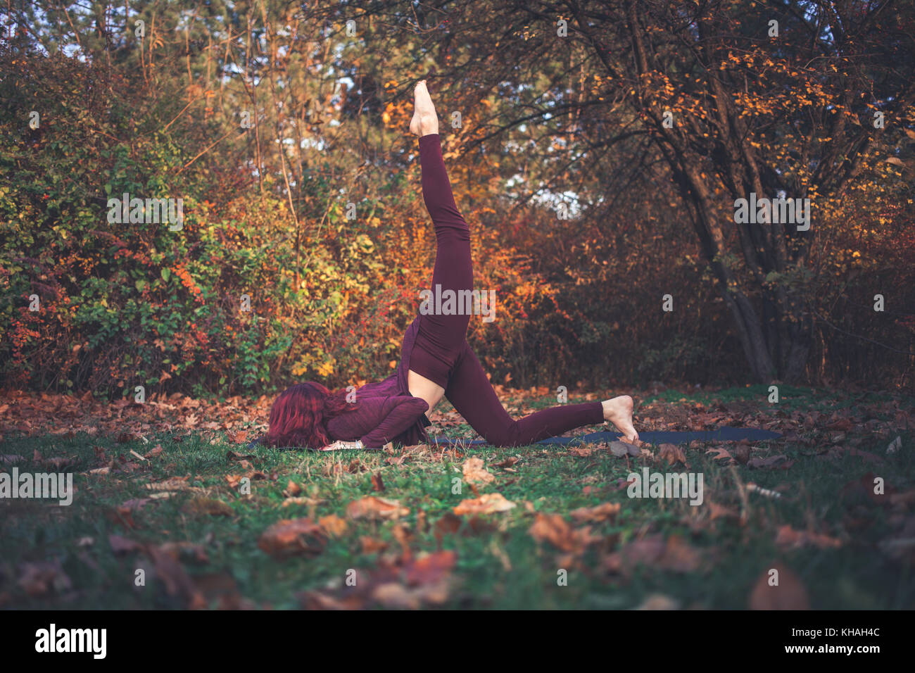 Fille sur un jour d'automne la pratique du yoga en plein air,faisant variation de huit à une jambe-limbed posent (eka pada) ashtangasana avec jambe soulevée vers le haut Banque D'Images