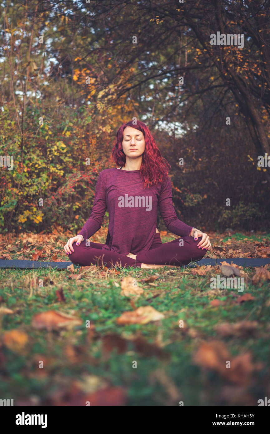 Fille sur un jour d'automne la pratique du yoga à l'extérieur, assis dans le facile (bon, agréable) posent (sukhasana) Banque D'Images