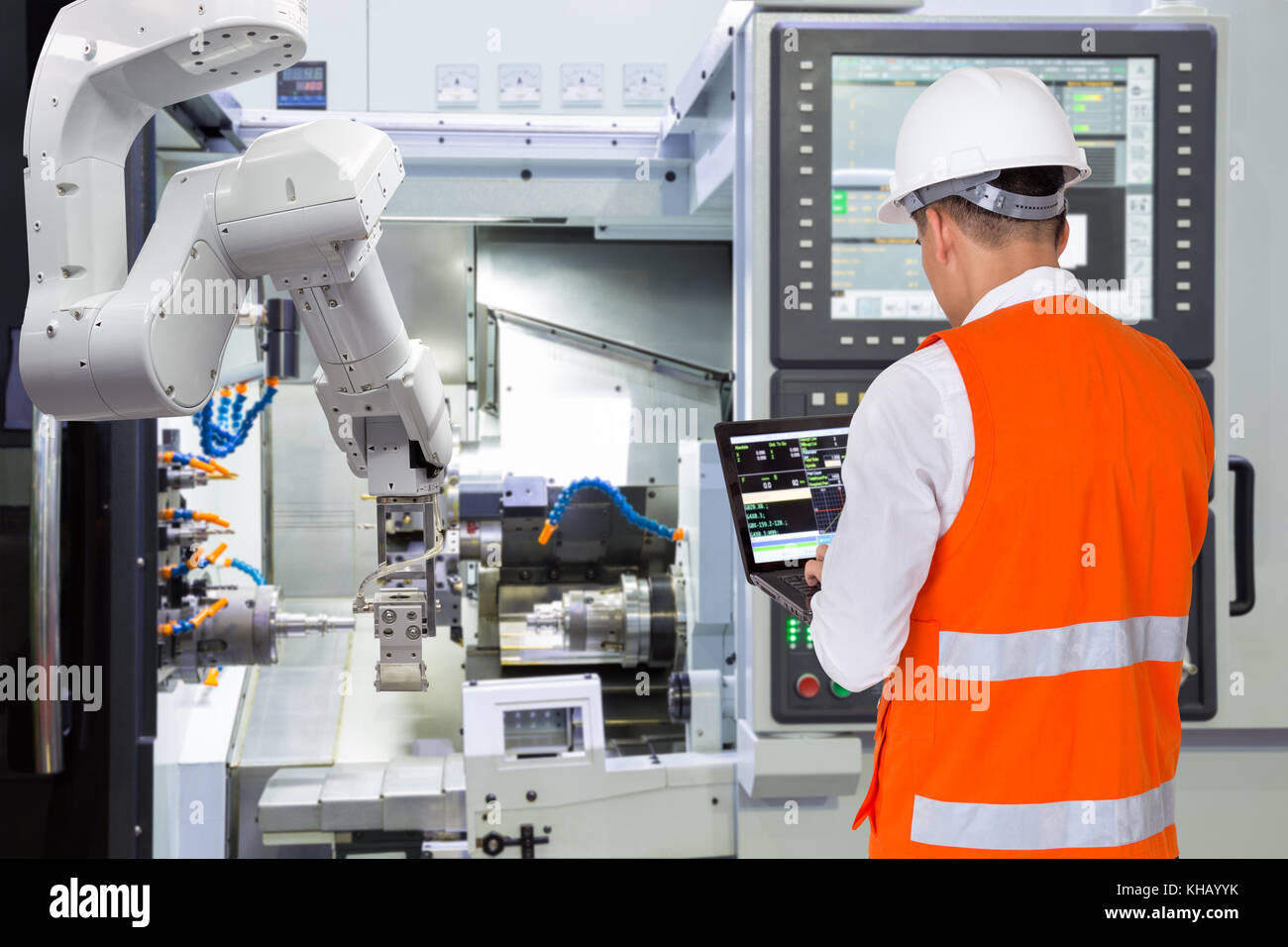 Ordinateur portable à l'aide de l'ingénieur de maintenance pour bras robotique automatique avec machine CNC dans smart factory. industrie 4.0 concept Banque D'Images