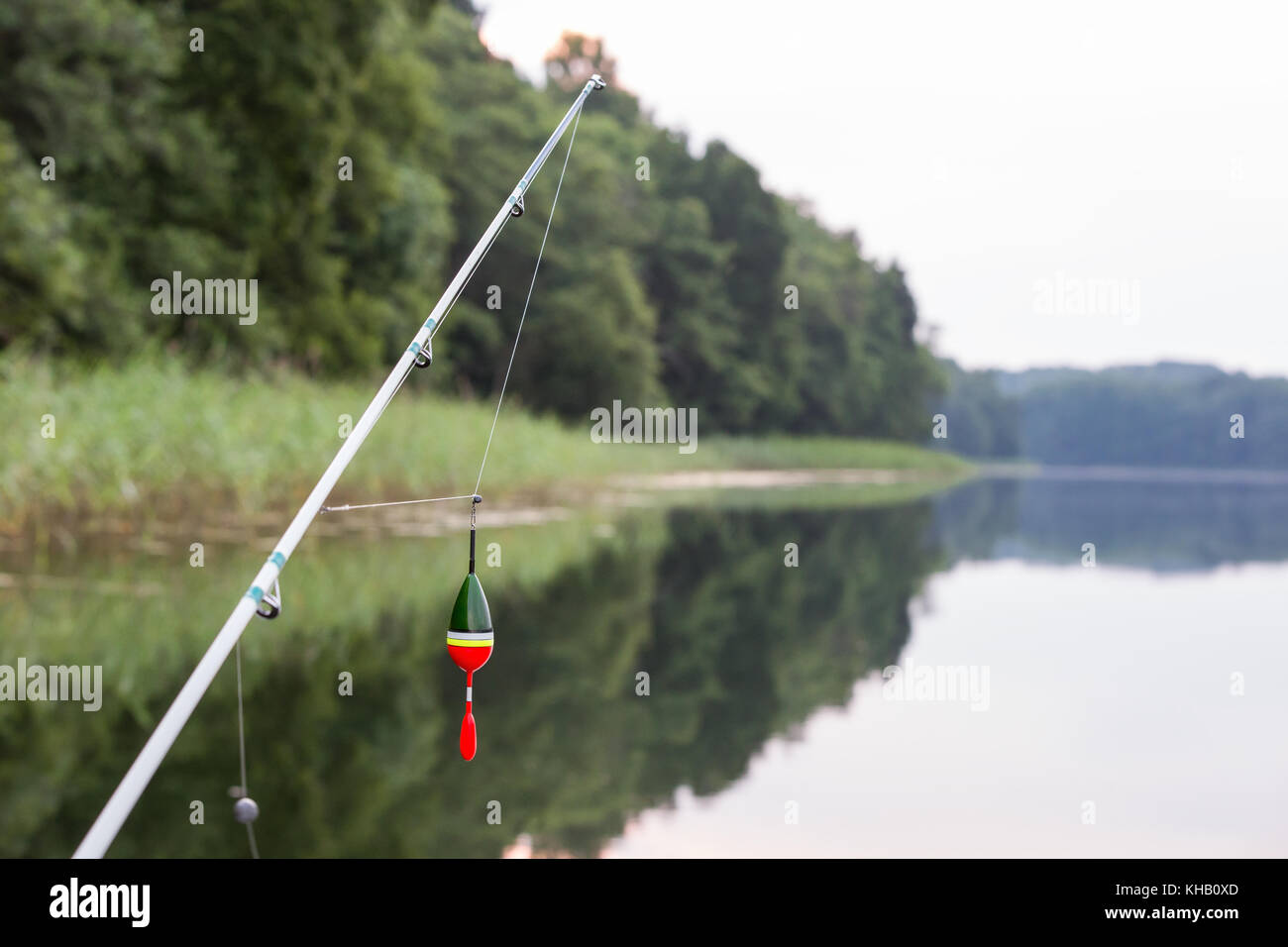 Canne à pêche, canne à pêche avec un bouchon ou flotter sur la ligne et un  lac colorés en arrière-plan Photo Stock - Alamy