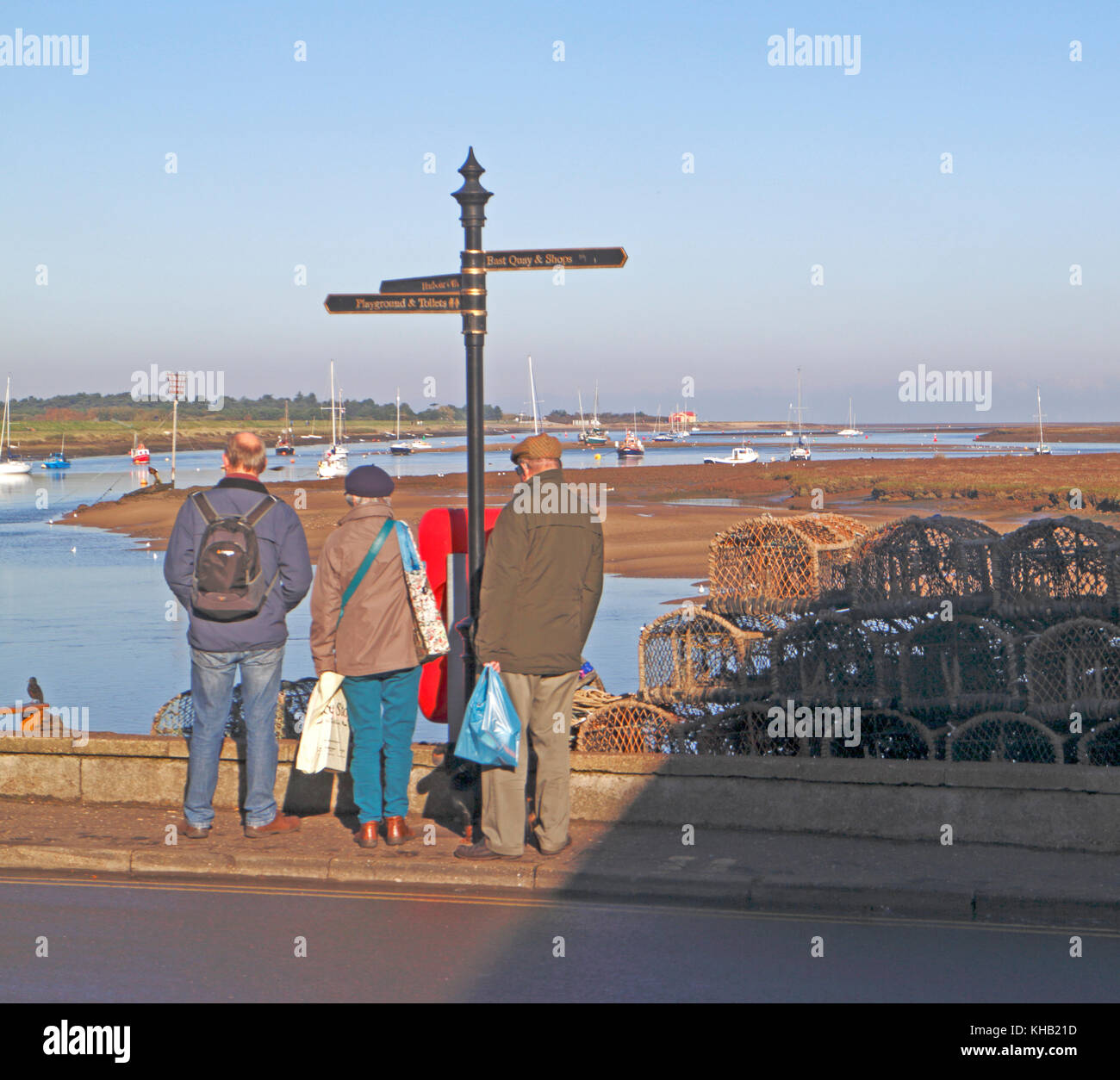 Une vue de trois personnes regardant au-dessus du quai jusqu'au port de Wells-next-the-Sea, Norfolk, Angleterre, Royaume-Uni. Banque D'Images