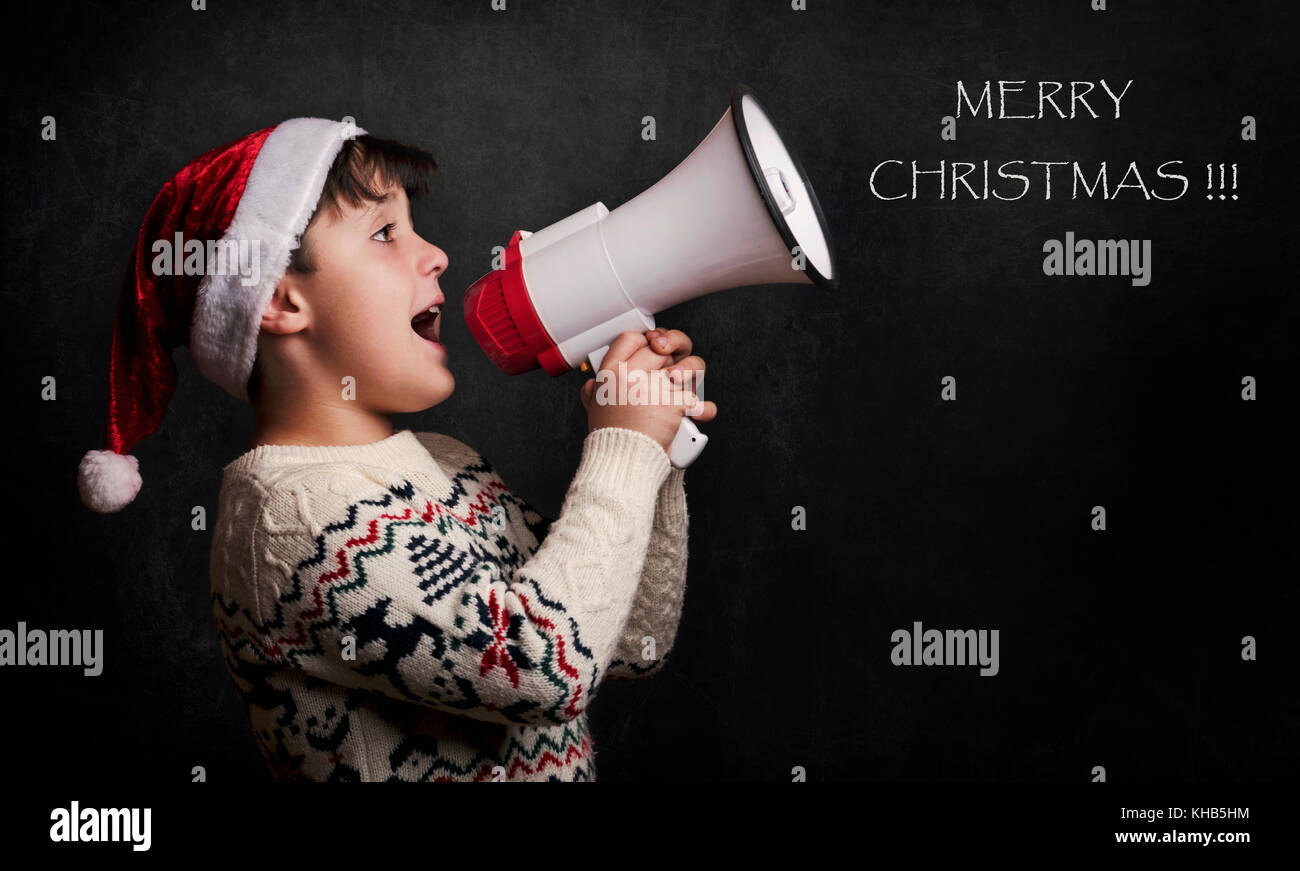 Garçon avec un mégaphone à Noël sur fond noir Banque D'Images