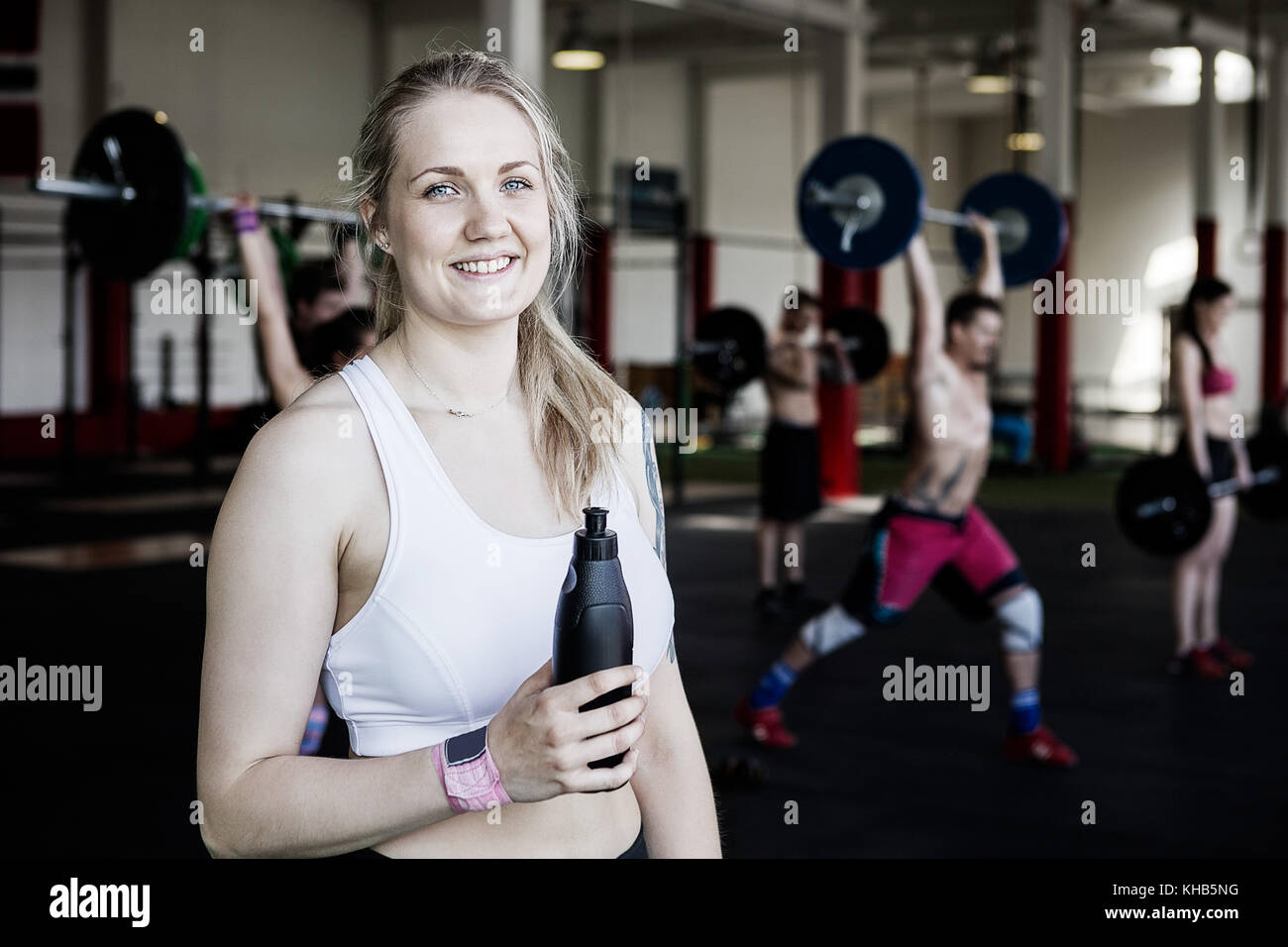 Portrait of young fit woman holding water bottle tout en se tenant dans une salle de sport Banque D'Images