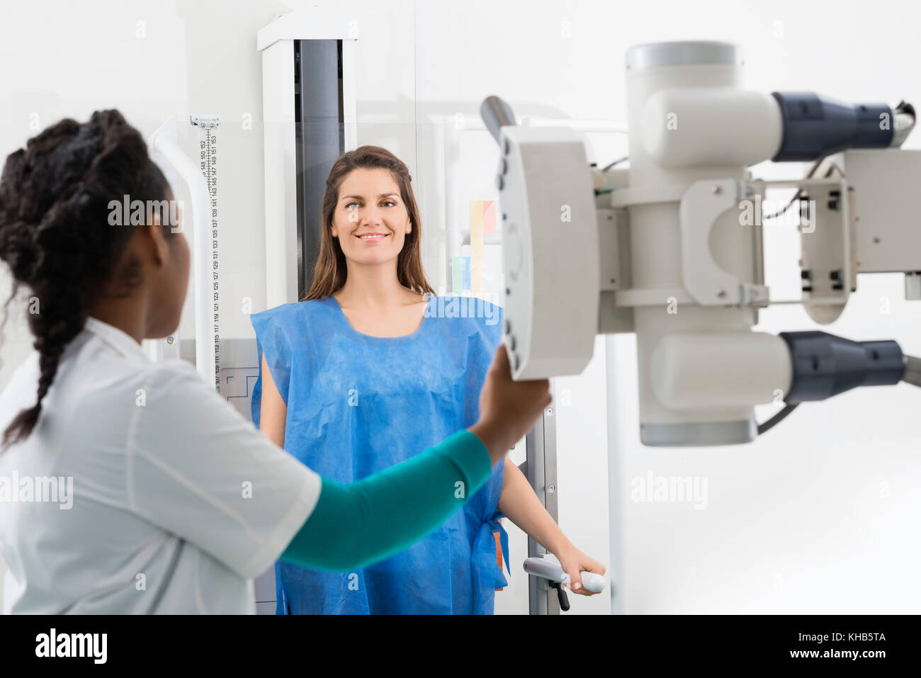 Jeune femme radiologue réglage de machine à rayons x sur le patient dans la salle d'examen Banque D'Images