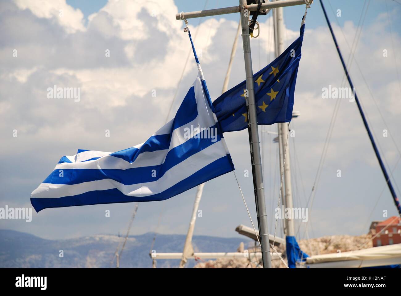 Un drapeau grec et un drapeau de l'Union européenne à voler d'un mât de bateau dans le port de emborio sur l'île grecque de Halki. Banque D'Images