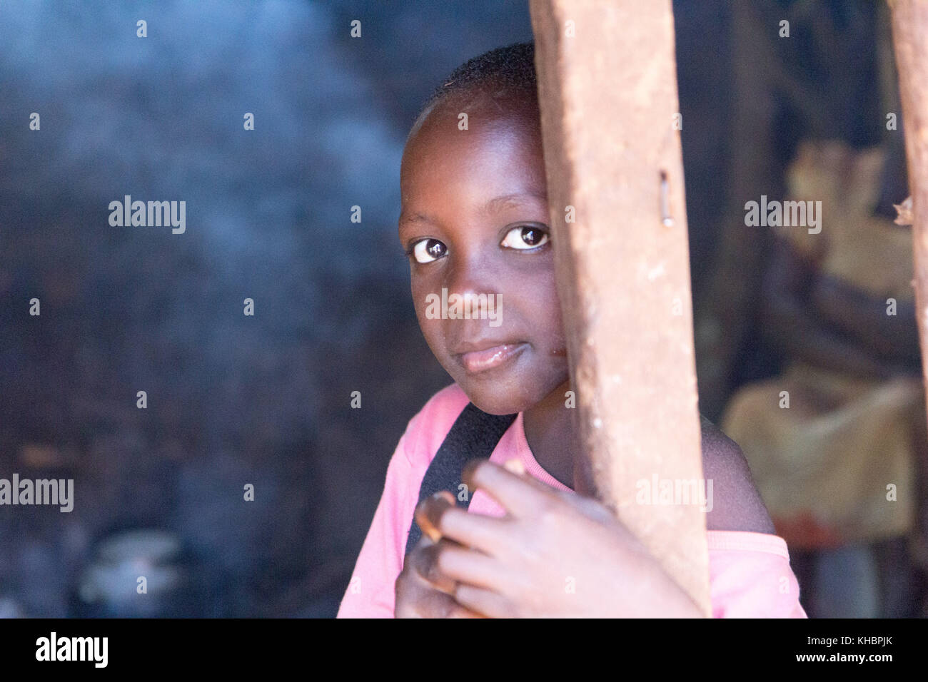 A smiling tween age girl à la porte d'une cuisine enfumée où des aliments sont préparés. Banque D'Images