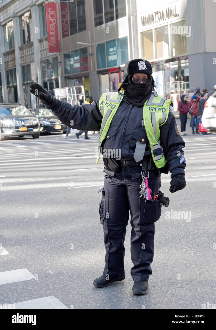 Une femme policière de diriger la circulation de voitures sur une journée très froide. Le sixième Ave. de l'Herald Square de Manhattan, New York City. Banque D'Images