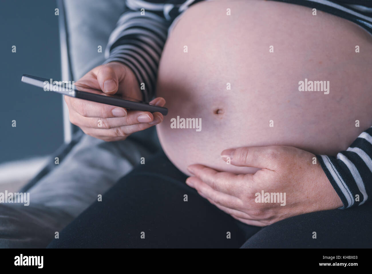 Femme enceinte en utilisant son smartphone pendant la grossesse Banque D'Images