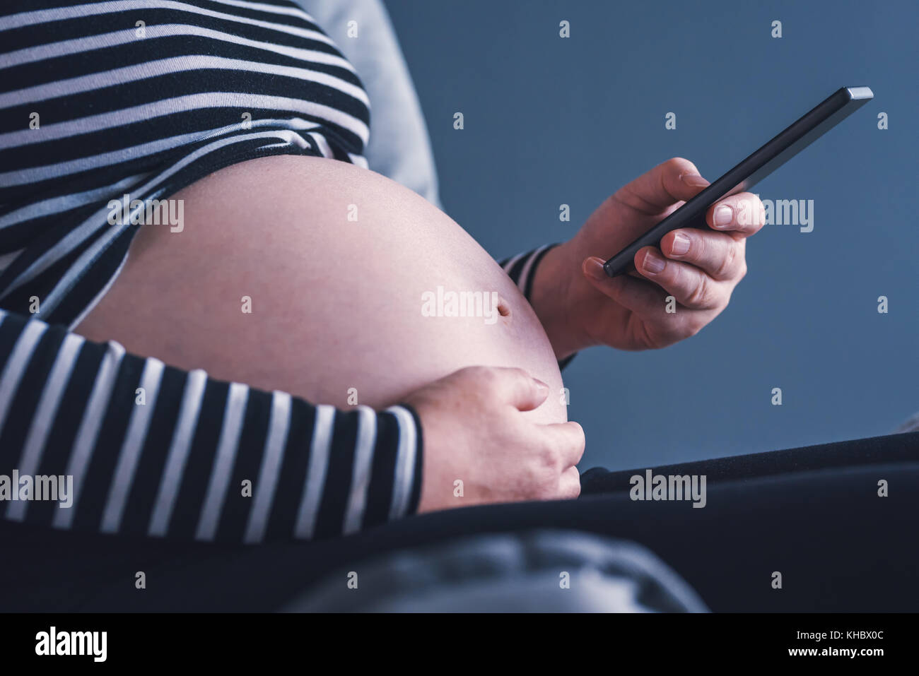 Femme enceinte en utilisant son smartphone pendant la grossesse Banque D'Images