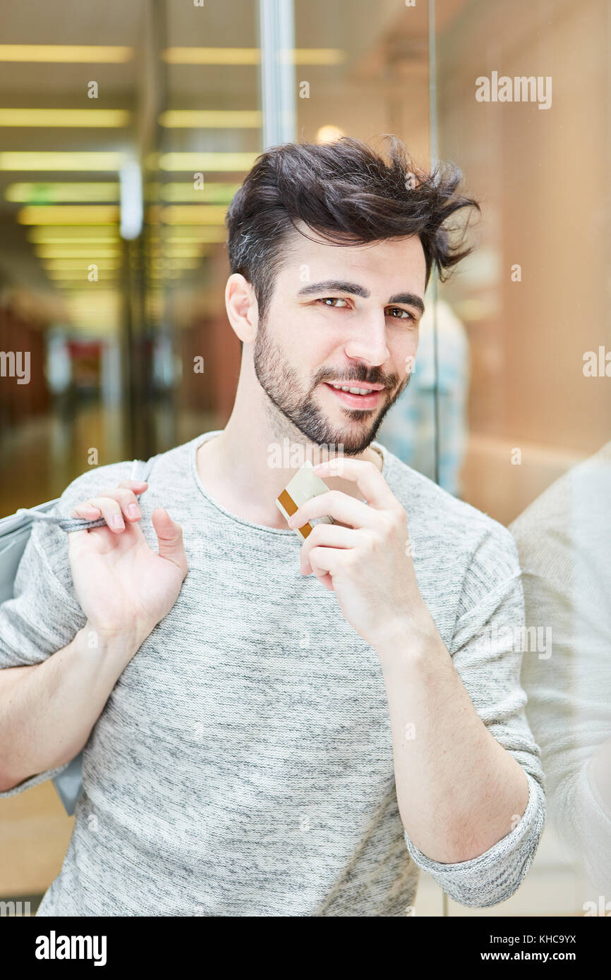 Jeune homme en tant que client et consommateur dans centre commercial avec carte de crédit Banque D'Images