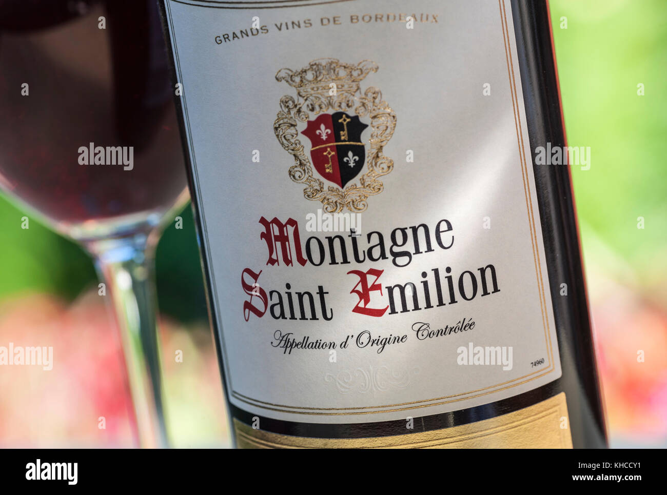 Montagne Saint Emilion vin ensoleillée avec étiquettes pour bouteilles de vin rouge derrière le verre de dégustation de vin floral en situation d'alfresco Banque D'Images