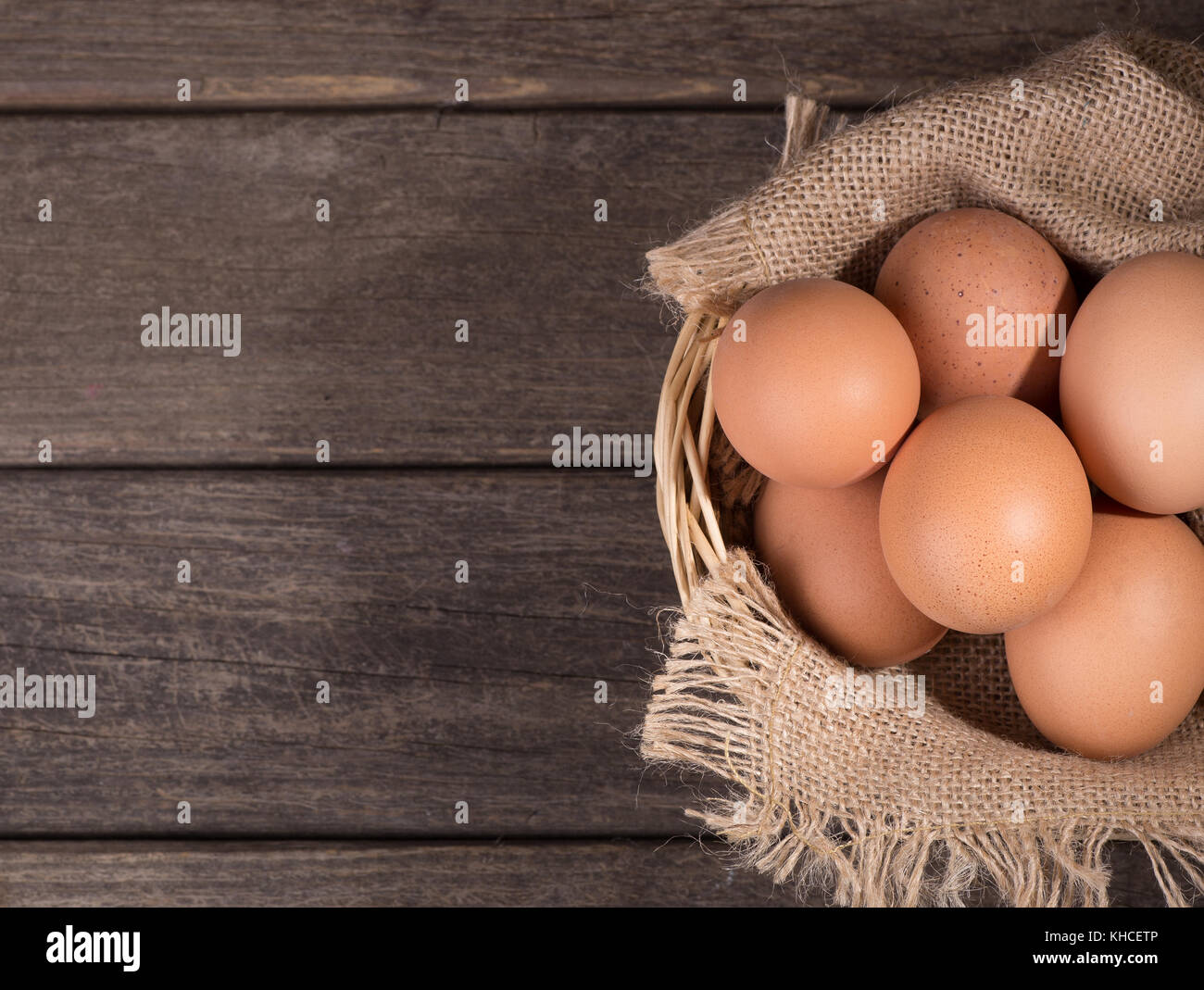 Brown oeufs dans un panier et sur une surface en bois Banque D'Images