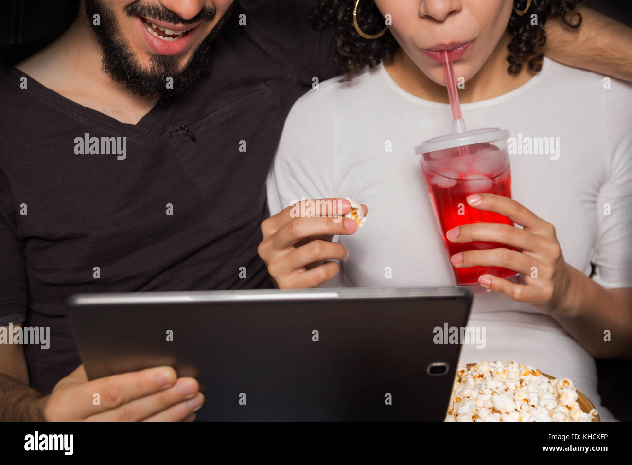 Sweet couple est regardant la vidéo sur tablette numérique. Ils sont eating popcorn et boisson. close up, sans visage. focus sélectif. eating popcorn et d Banque D'Images