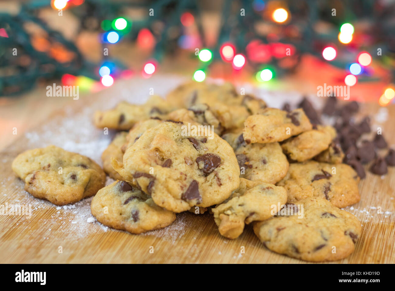 Des cookies aux pépites de chocolat sur planche de bois avec des lumières colorées en arrière-plan, selective focus Banque D'Images