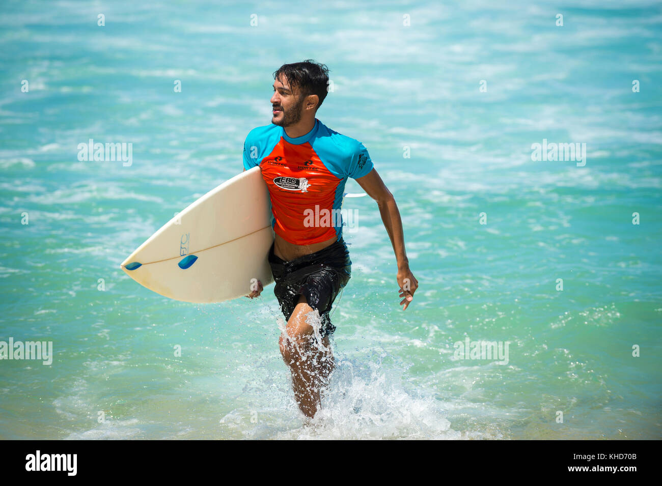 RIO DE JANEIRO - le 9 février 2017 : jeune surfeur brésilien se promène avec son surf à travers les vagues à l'Arpoador, spot de surf populaire. Banque D'Images
