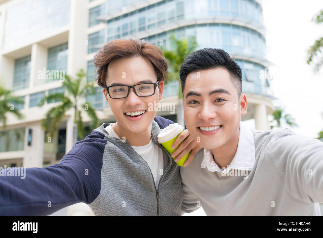 Deux jeunes hommes d'affaires gais et permanent en tenant en selfies office Banque D'Images