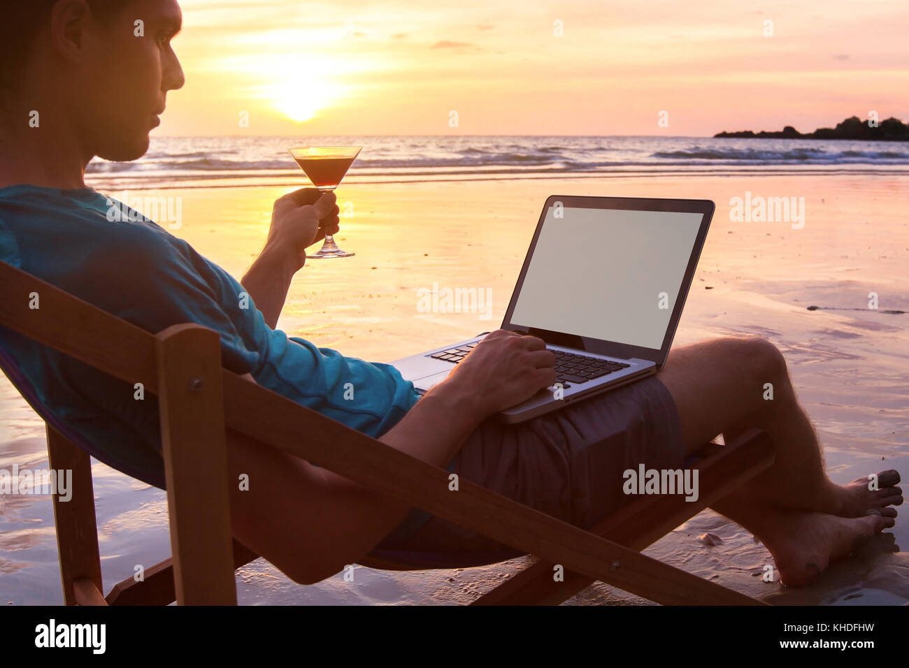 Homme d'affaires indépendant travaillant sur ordinateur à sunset beach, ordinateur portable avec écran vide et copyspace Banque D'Images