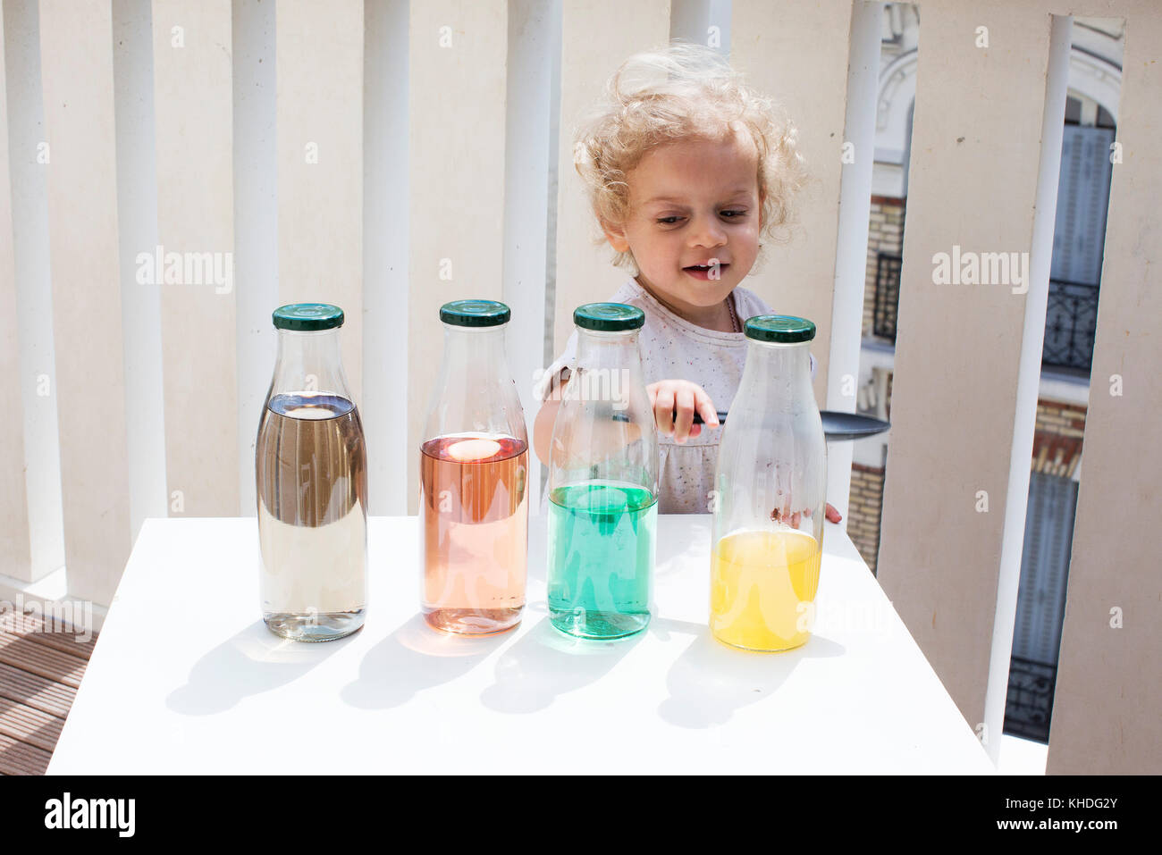 Petite fille des sons en appuyant sur des bouteilles d'eau Banque D'Images