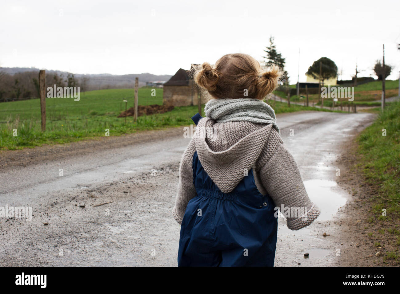 Petite fille qui marche le long chemin de terre humide Banque D'Images