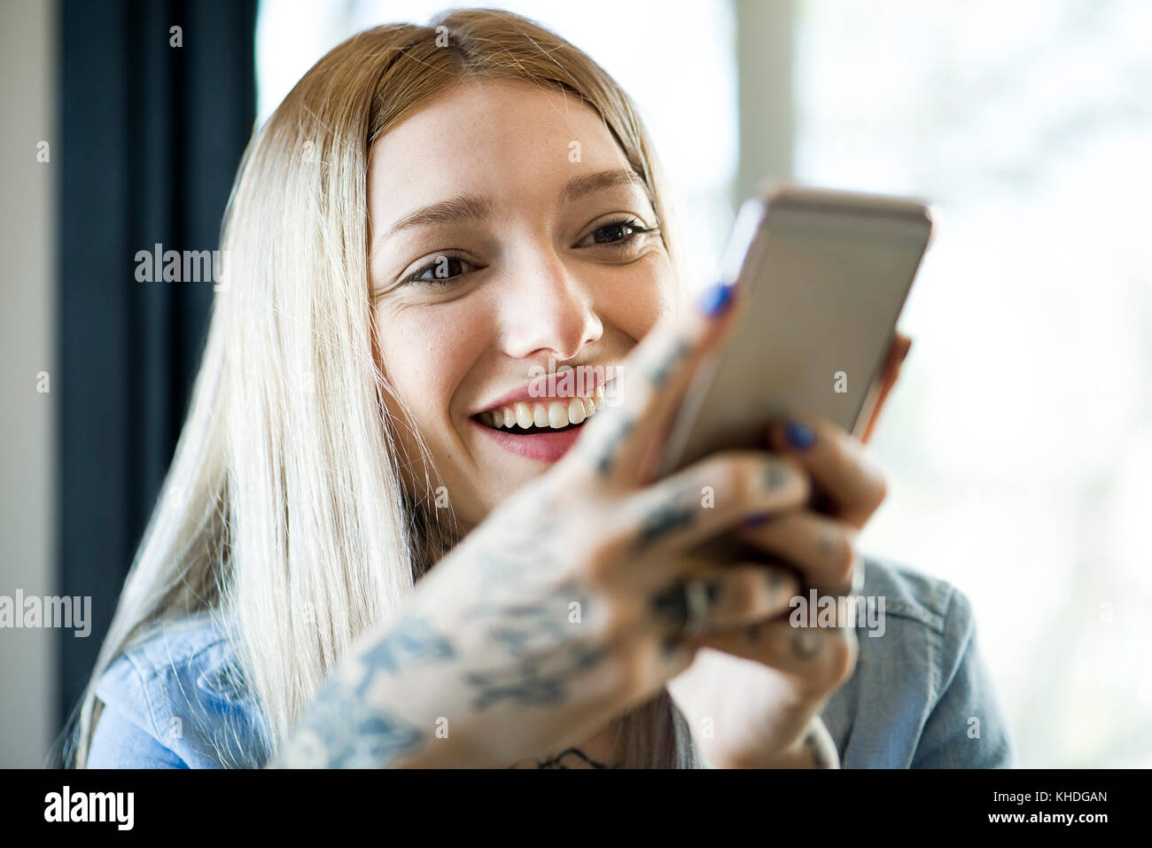 Woman using smartphone et souriant gaiement Banque D'Images