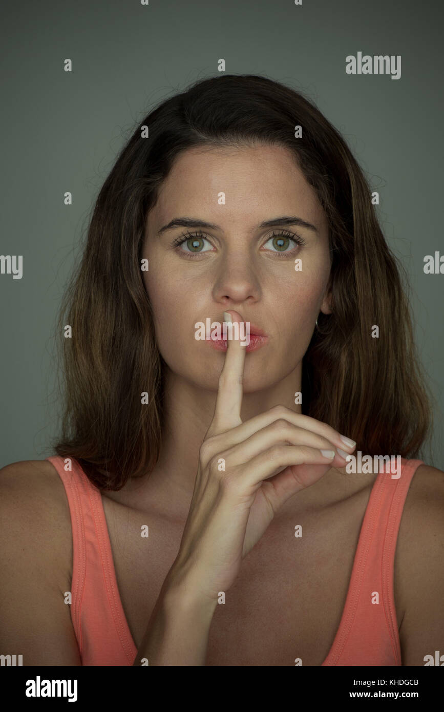 Jeune femme tenant collés contre les lèvres en silence, portrait Banque D'Images