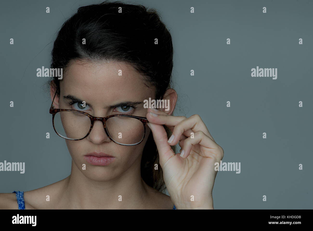Jeune femme à la recherche sur le haut de ses lunettes, fronçant, portrait Banque D'Images